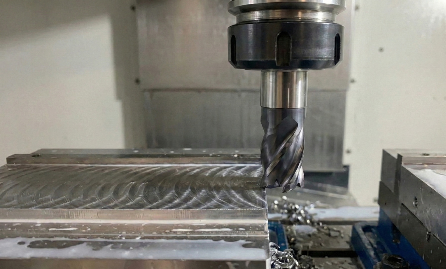 Frez monolityczny Osawa HF podczas obróbki bloku stalowego na frezarce CNC, widoczne wióry i charakterystyczne ślady po narzędziu.