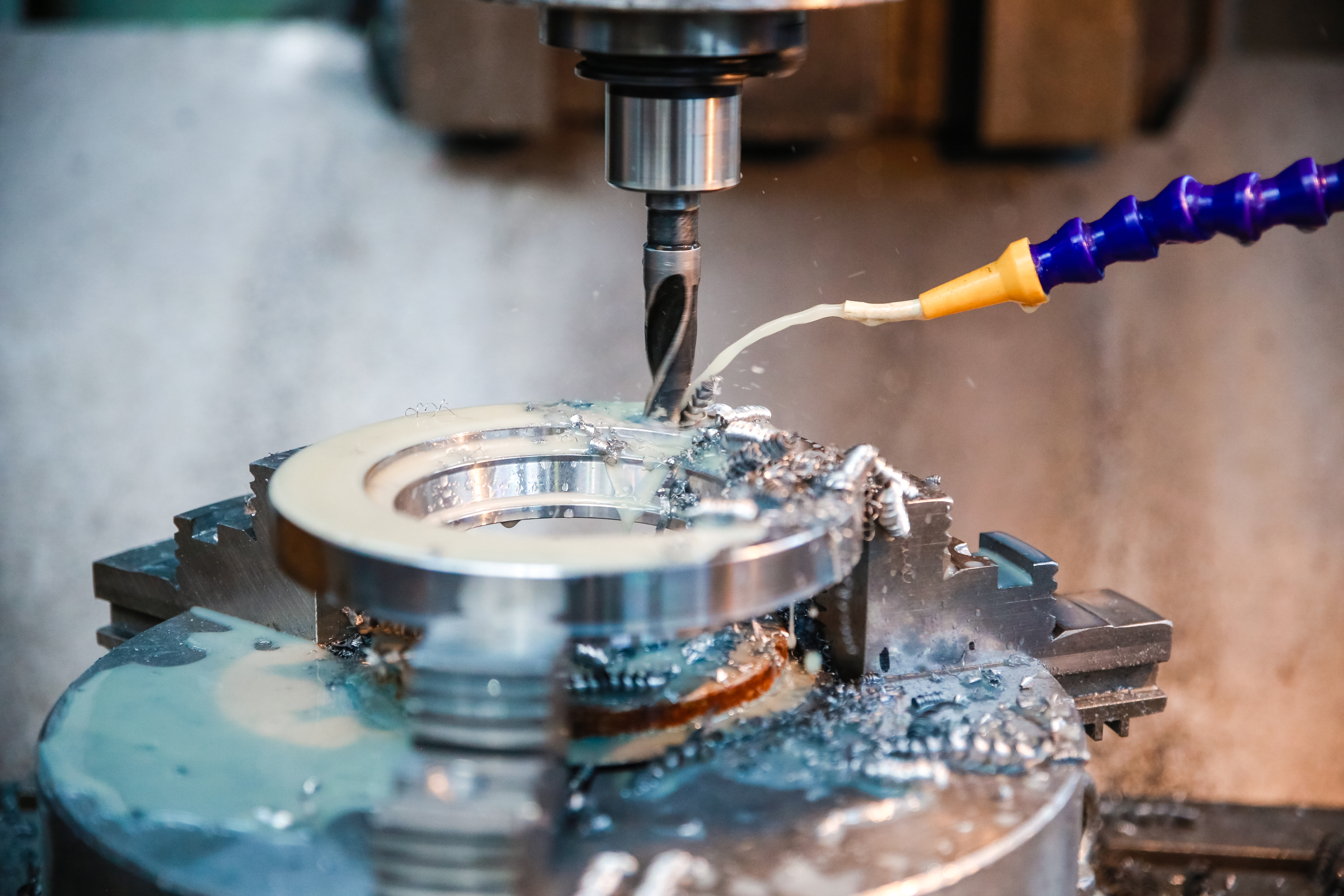 Wiertło cnc obrabia otwór w wyrobie metalowym na który leci chłodziwo.