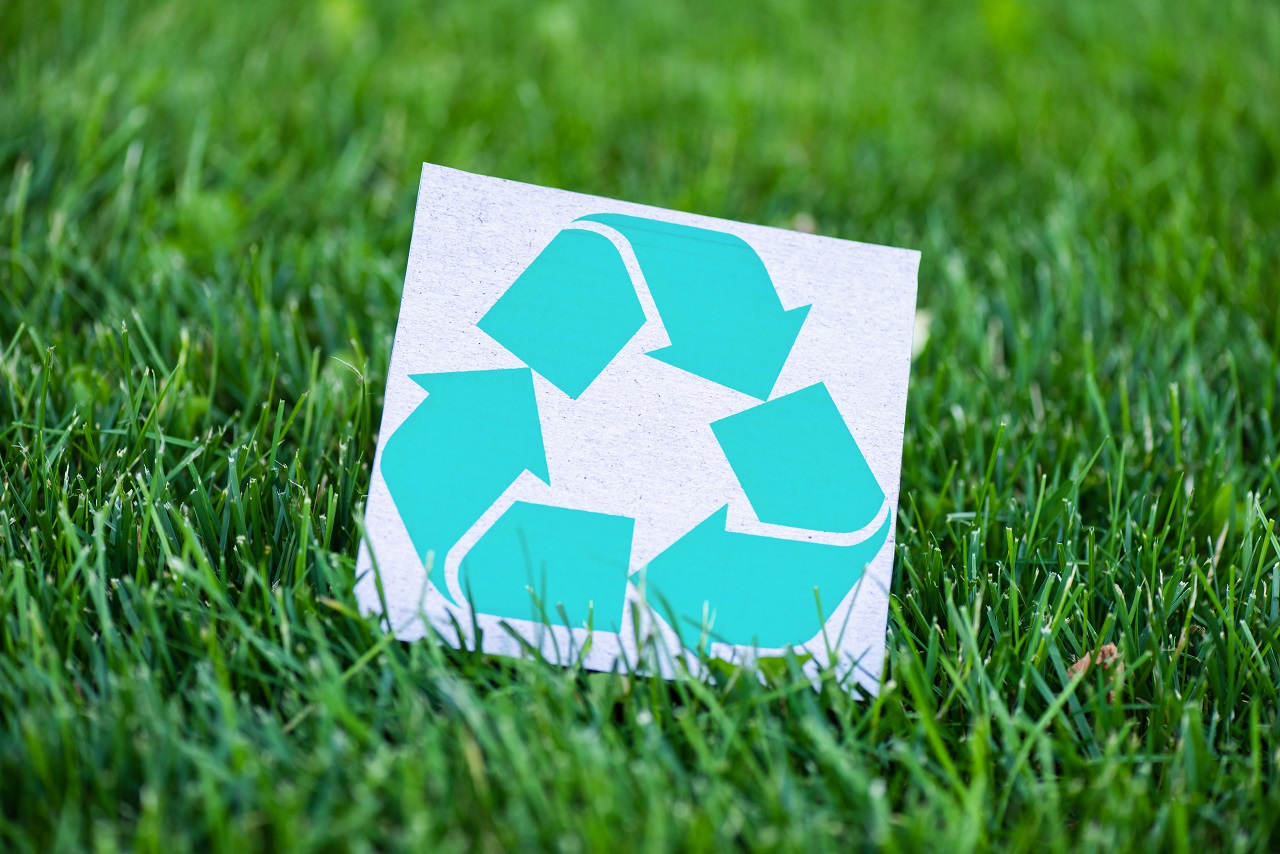 Kartka z logo recyklingu na trawie